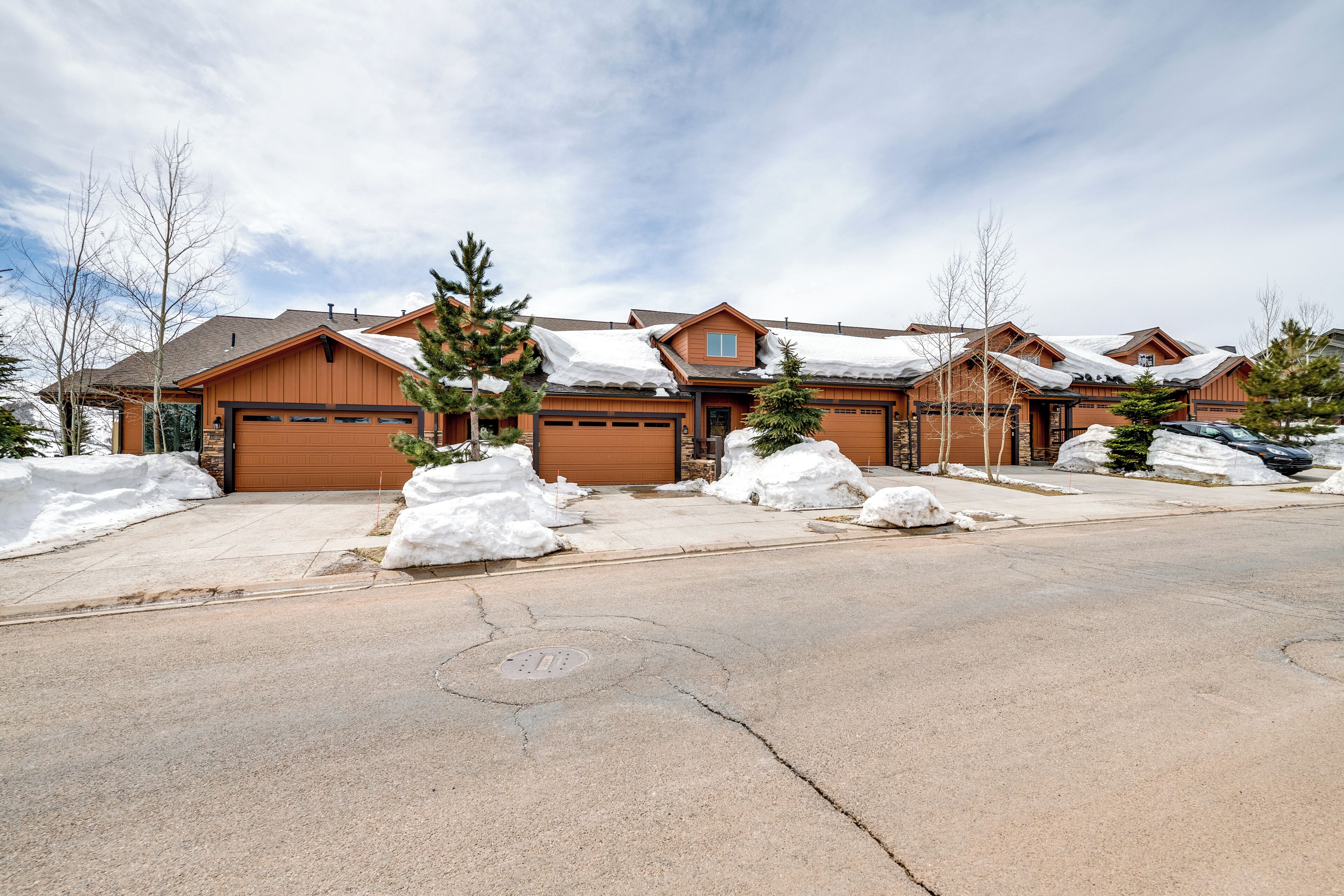 A residential area with multiple houses, each with a garage and covered by snow.