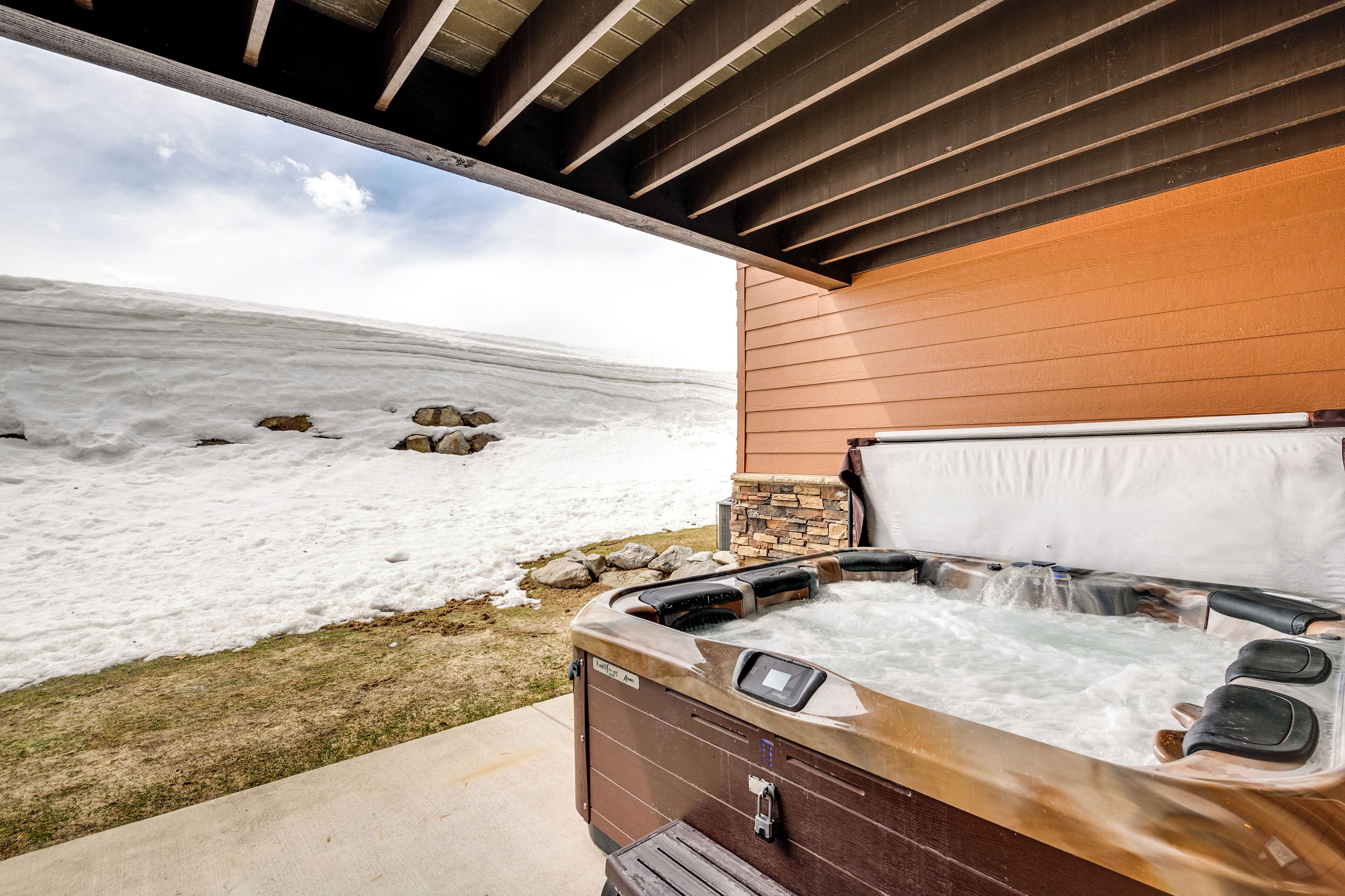 Ein Whirlpool unter einer Holzpergola mit Blick auf eine verschneite Landschaft.