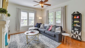 A living room with a gray sofa, a white coffee table, a ceiling fan, and a black and white patterned bookshelf.