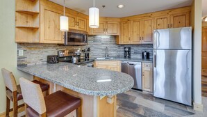 A kitchen with wooden cabinets, granite countertops, stainless steel appliances, and pendant lighting. - Ski-in/ski-out Park City Condo: Fireplace & View! (Park City)