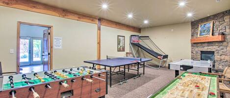 A room with a foosball table, ping pong table, and shuffleboard table.