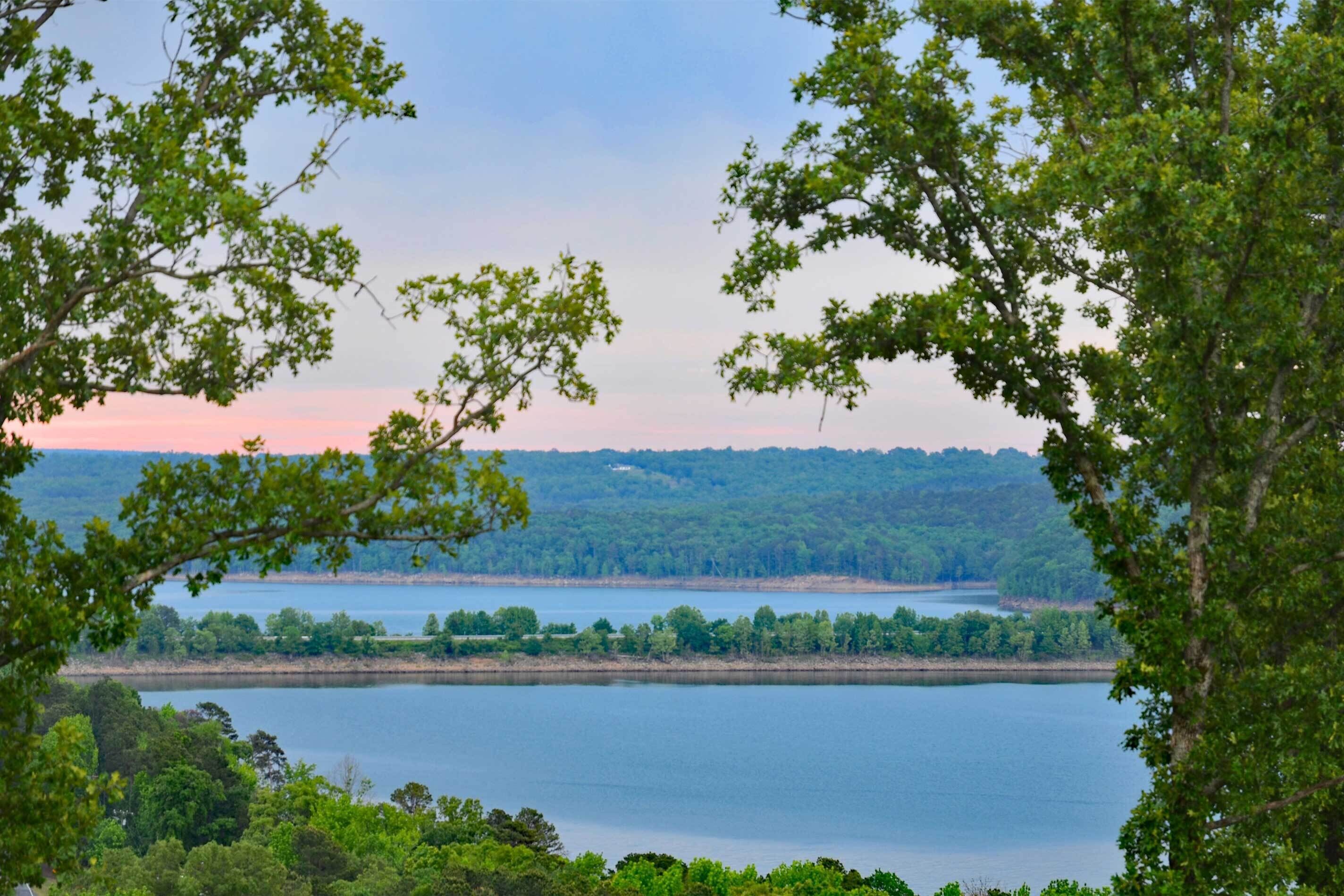 Un lago rodeado de un bosque denso, con vistas despejadas al agua y colinas distantes.