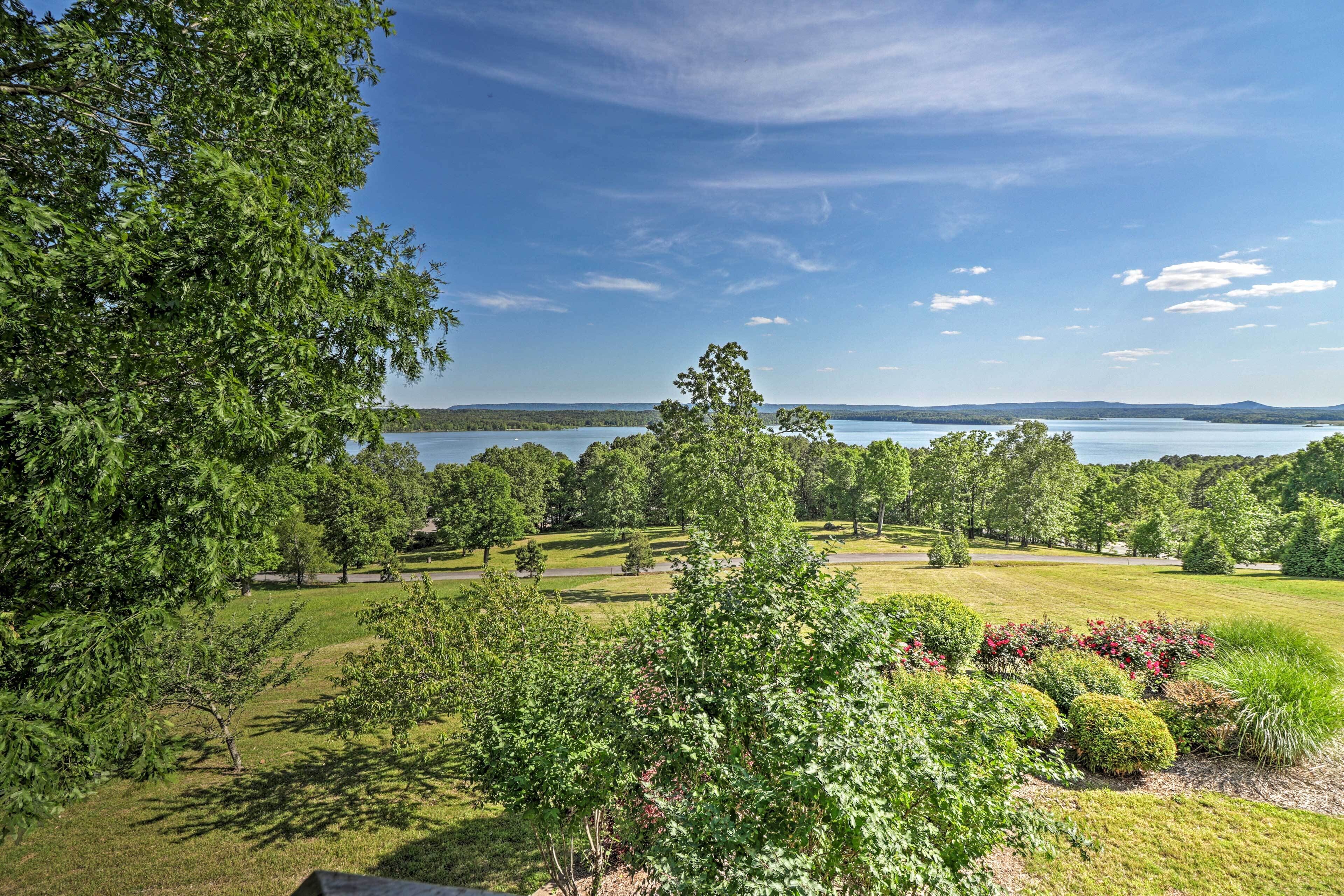 A lush landscape with a lake, trees, and manicured lawns.