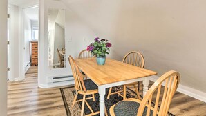 A dining area with a wooden table and chairs, a vase with flowers, and a view of a hallway with a wooden dresser. - Brunswick Retreat < 1 Mi to Potomac River! (Brunswick)