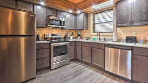 A modern kitchen with stainless steel appliances, wooden cabinets, and a large window. - Pigeon Forge Cabin w/ Hot Tub: 1 Mi to Parkway (Pigeon Forge)