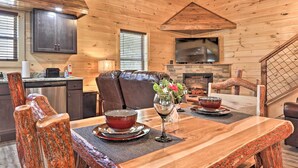 A wooden interior with a dining table, chairs, a sofa, and a fireplace. - Pigeon Forge Cabin w/ Hot Tub: 1 Mi to Parkway (Pigeon Forge)
