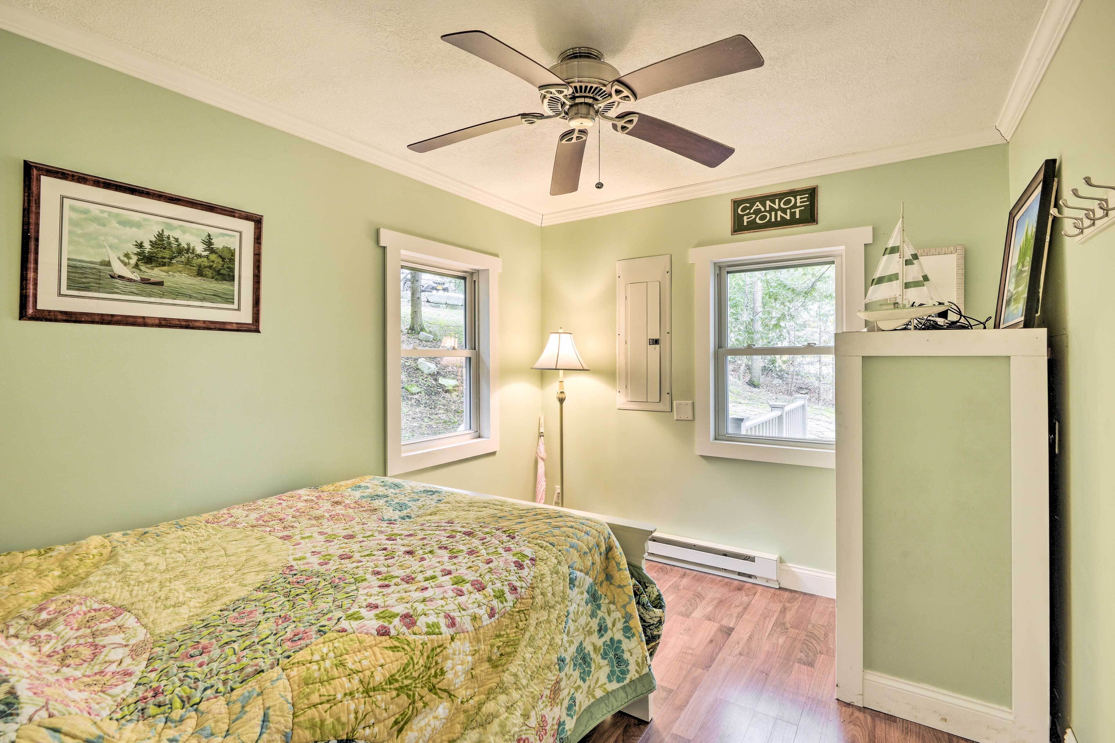 Une chambre à coucher avec un lit, un ventilateur de plafond, une fenêtre, une lampe et un panneau indiquant « Canoe Point ».