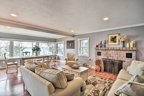 Un salon spacieux doté d’une cheminée, de grandes fenêtres et d’un coin salon confortable.