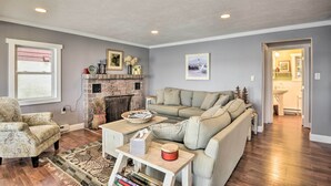 Un salon avec une cheminée, un canapé, une table basse et un fauteuil à motifs.