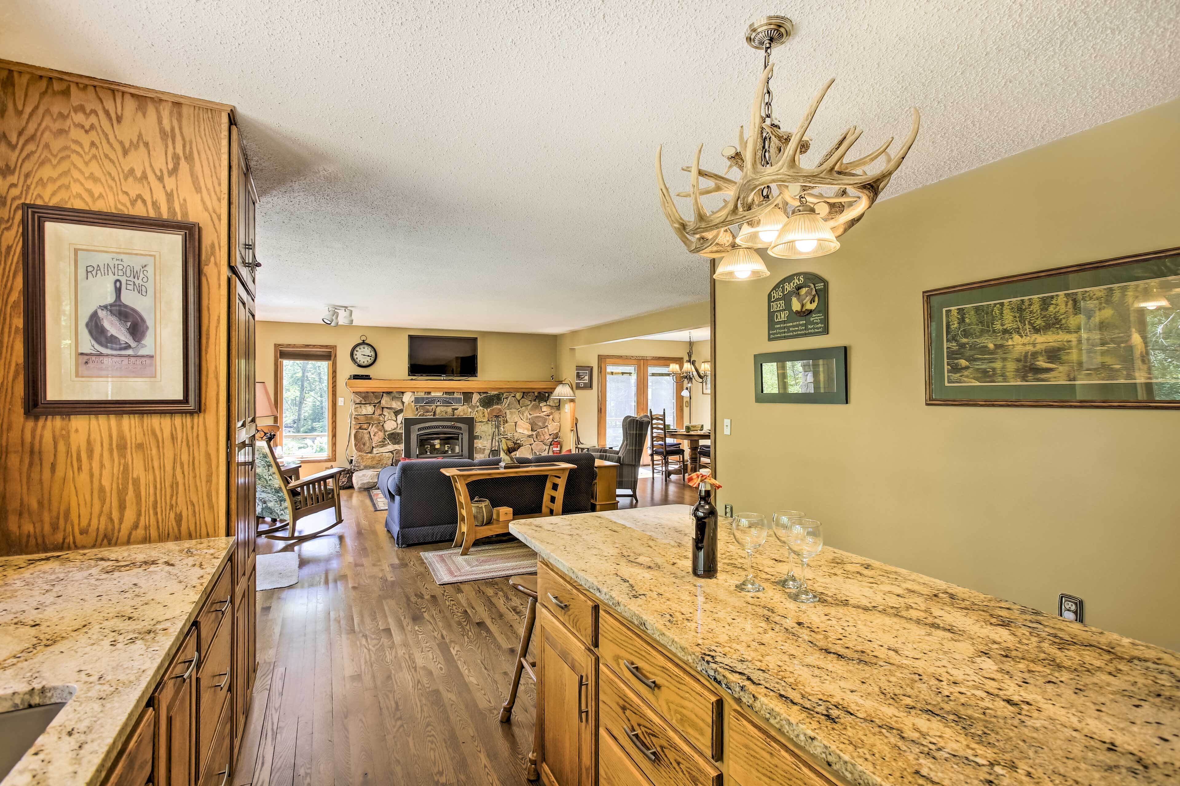 A spacious kitchen with granite countertops, wooden cabinets, and a stone fireplace.