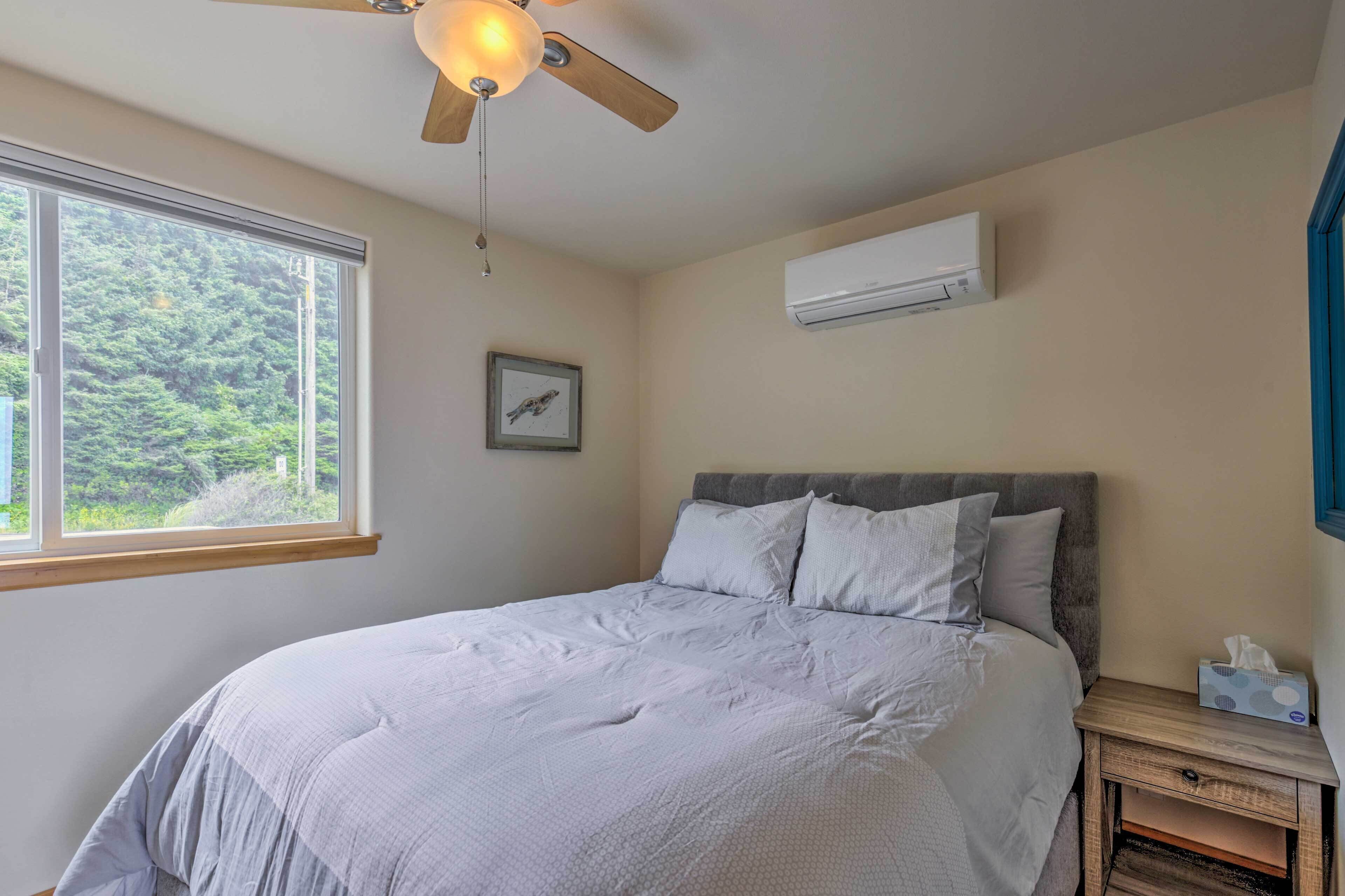A bedroom with a bed, a ceiling fan, a window, and an air conditioning unit.
