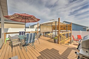A wooden deck with outdoor furniture, a grill, and a covered area with a table and chairs. - Spacious Family Home w/ Large Deck & Fire Pit! (Caldwell)
