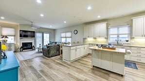 A spacious kitchen with white cabinets, a central island, and a fireplace. - Sunny Brigantine Townhome: Walk to Beach (Brigantine)