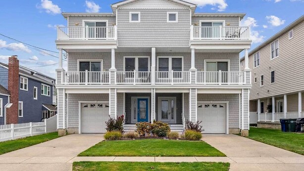 A two-story residential building with a front porch, two balconies, and a garage. - Sunny Brigantine Townhome: Walk to Beach (Brigantine)