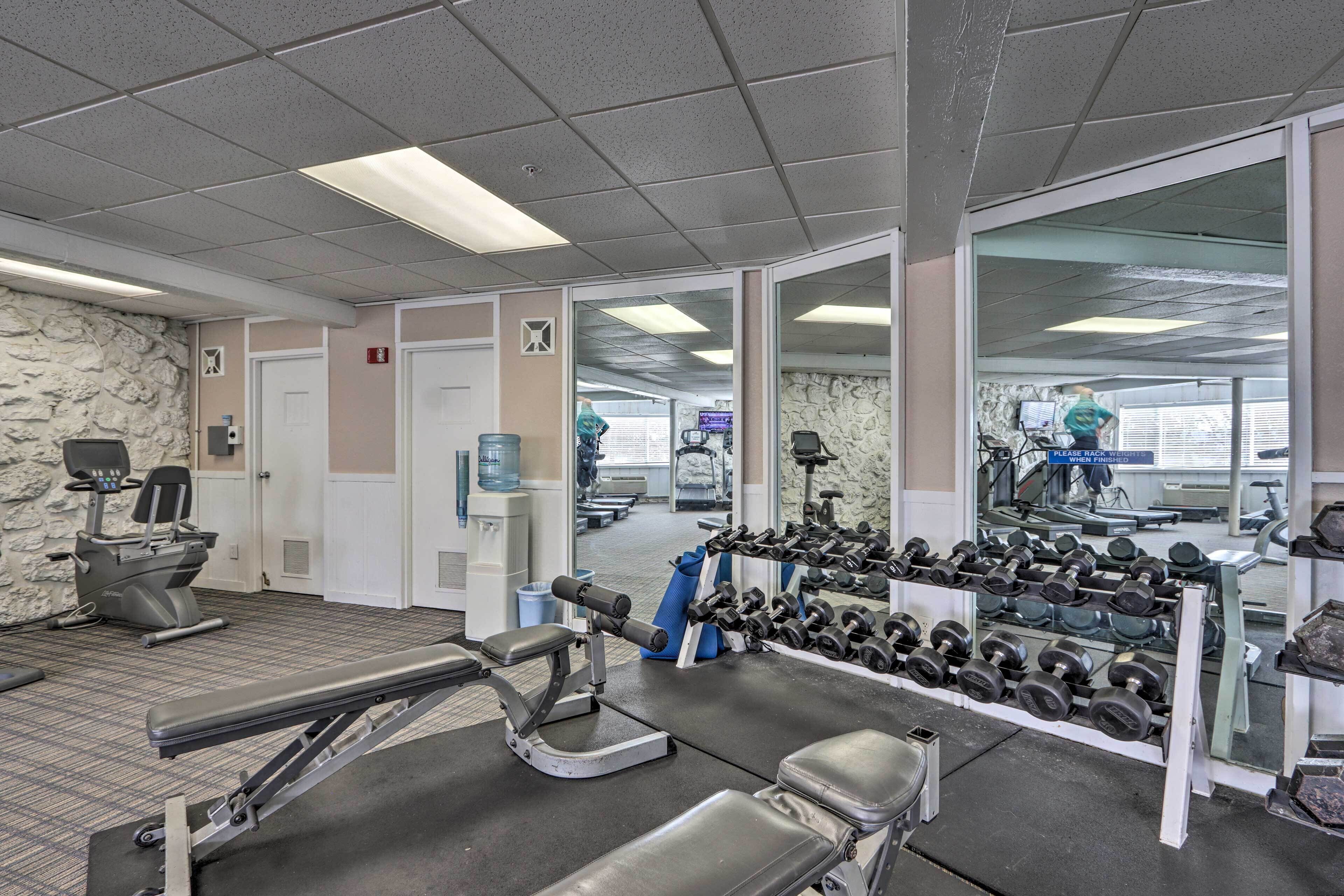 A gym with exercise equipment, a water cooler, and a mirror reflecting the gym area.