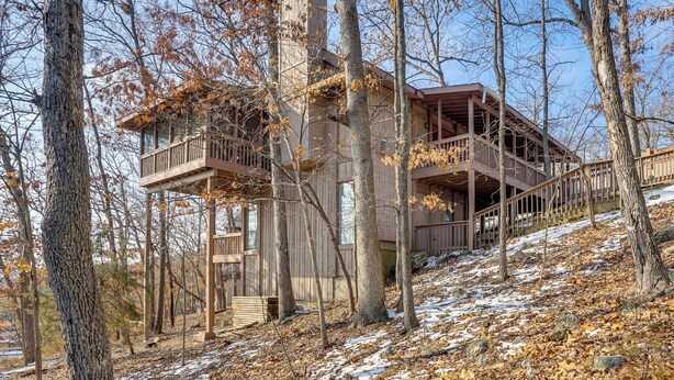 A cabin with a wooden exterior, multiple balconies, and a staircase leading to the upper levels. - Resort Living on Lake of the Ozarks! Family Cabin (Osage Beach)