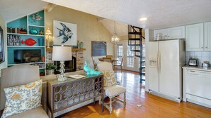 A spacious living area with a wooden floor, a sofa, a coffee table, and a kitchen with a refrigerator and cabinets. - Resort Living on Lake of the Ozarks! Family Cabin (Osage Beach)