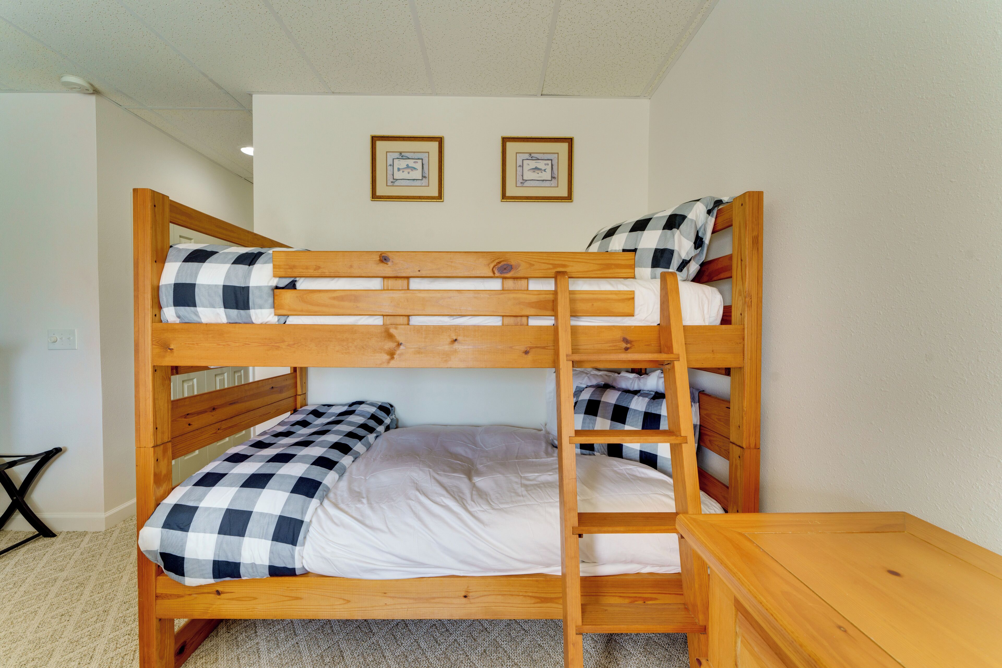 Un letto a castello con struttura in legno, due cuscini e un piccolo tavolino accanto.