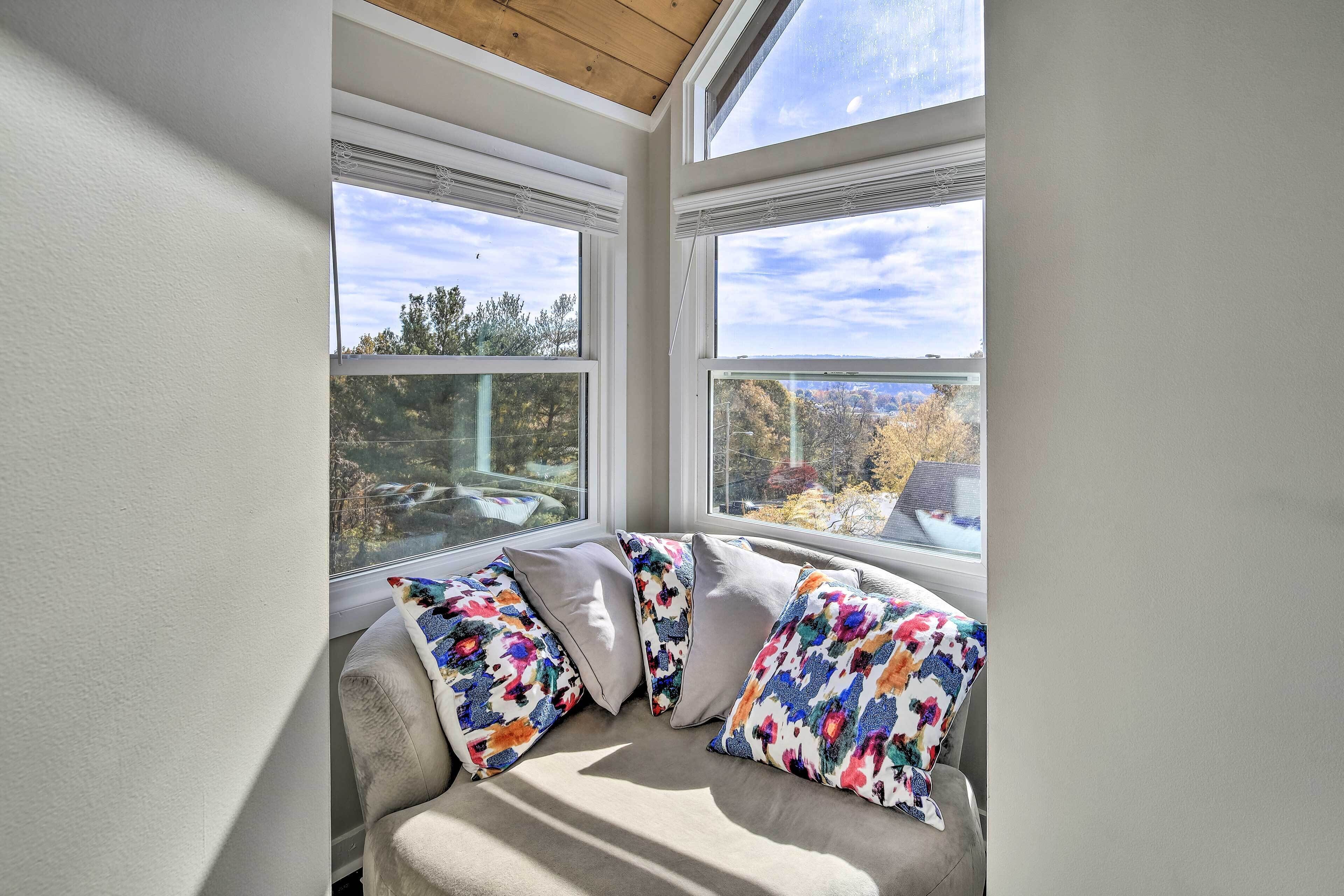 A corner seating area with a cushioned bench and two windows offering a view of trees and a distant landscape.