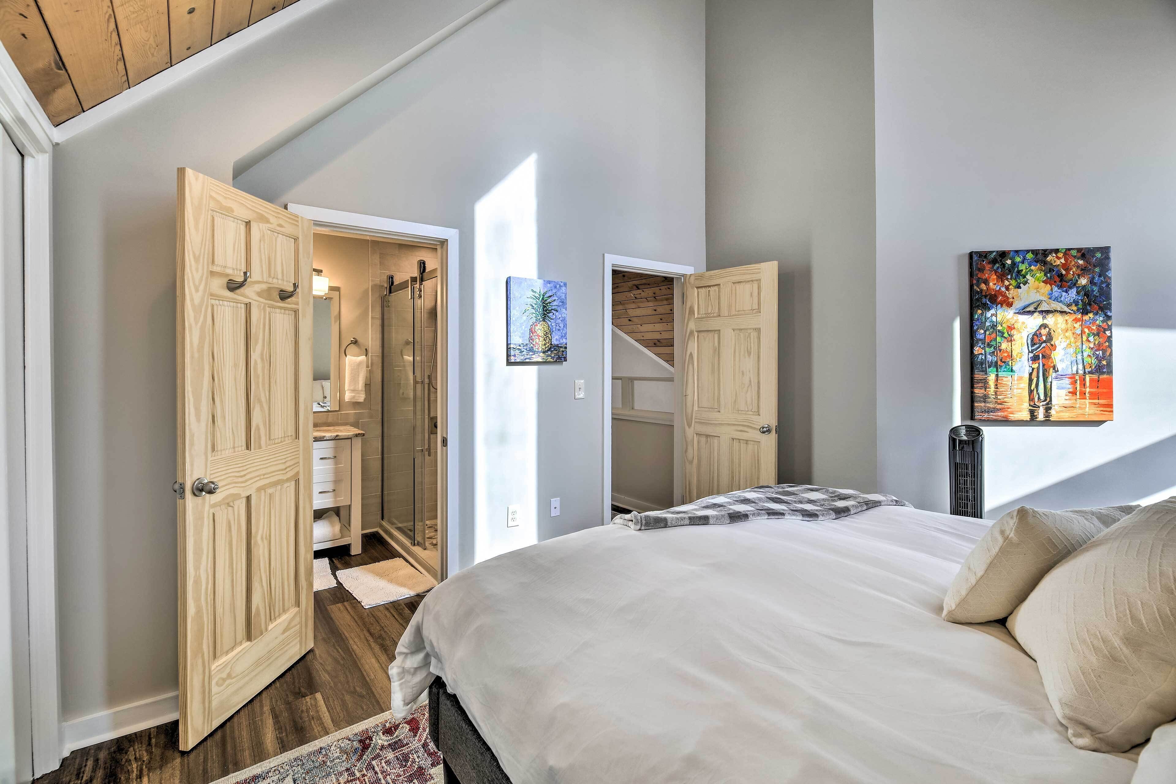A bedroom with a large bed, wooden wardrobe, and a bathroom visible through an open door.