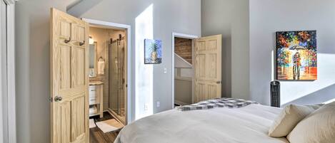 A bedroom with a large bed, wooden wardrobe, and a bathroom visible through an open door.