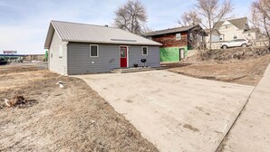 A single-story house with a red door, a small porch, and a concrete driveway. - Pierre Vacation Rental w/ Grill & Fenced Yard (Pierre)