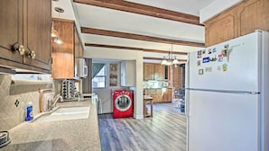 A modern kitchen with wooden cabinets, a built-in washing machine, and a refrigerator. - Quaint La Mesa Home With Beautiful Sunsets! (La Mesa)