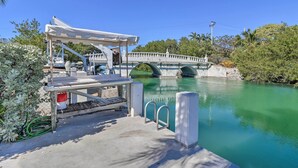 A dock with a covered seating area, a bridge, and a calm body of water. - Marathon Vacation Rental With Pool Access! (Marathon)