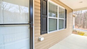 Une maison avec une porte de garage, une fenêtre avec des stores et un porche en béton.