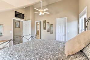 A bedroom with a patterned bedspread, a ceiling fan, and framed pictures on the walls. - Lakefront Camdenton Home w/ Fire Pit & Grill! (Camdenton)