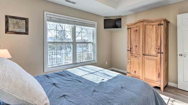 A bedroom with a large bed, a window with blinds, a wooden wardrobe, and a ceiling fan. - Lakefront Camdenton Home w/ Fire Pit & Grill! (Camdenton)