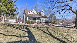 A two-story house with a front porch, a garage, and a driveway. - Lakefront Camdenton Home w/ Fire Pit & Grill! (Camdenton)