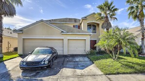A two-story house with a garage, a parked car, and palm trees. - Orlando Home w/ Private Yard + Patio! (Orlando)
