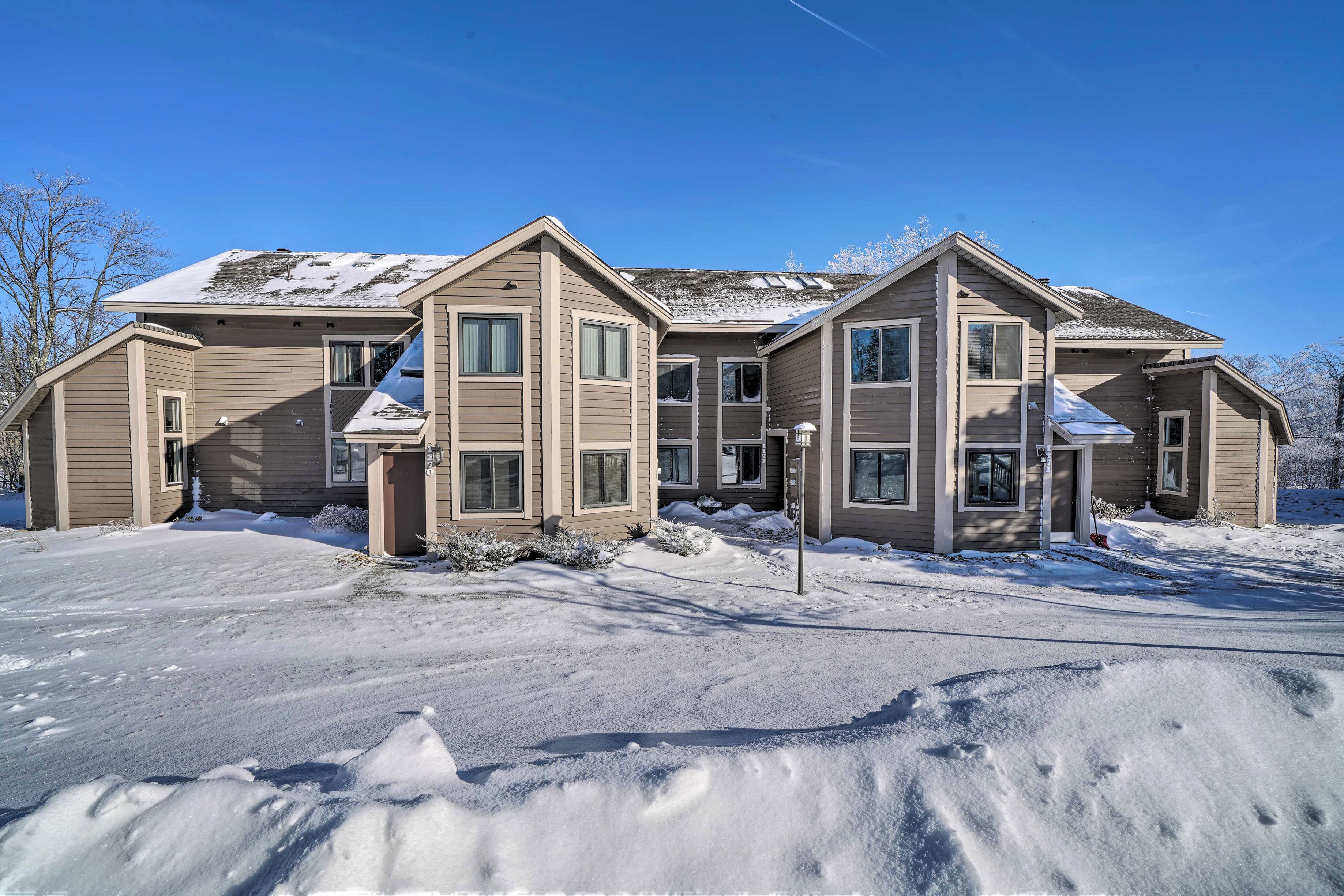 A multi-story residential building with a symmetrical facade, multiple windows, and a snow-covered roof.
