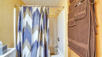 Une salle de bain équipée d’un rideau de douche, d’une baignoire et d’un porte-serviettes avec des serviettes.