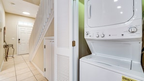 A laundry room with a stacked washer and dryer, a staircase, and a door leading to another room. - 6 Mi to Disney: Resort Home w/ Pool Access! (Kissimmee)