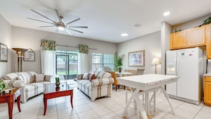 A spacious living room with a ceiling fan, two sofas, a coffee table, and a dining table. - 6 Mi to Disney: Resort Home w/ Pool Access! (Kissimmee)