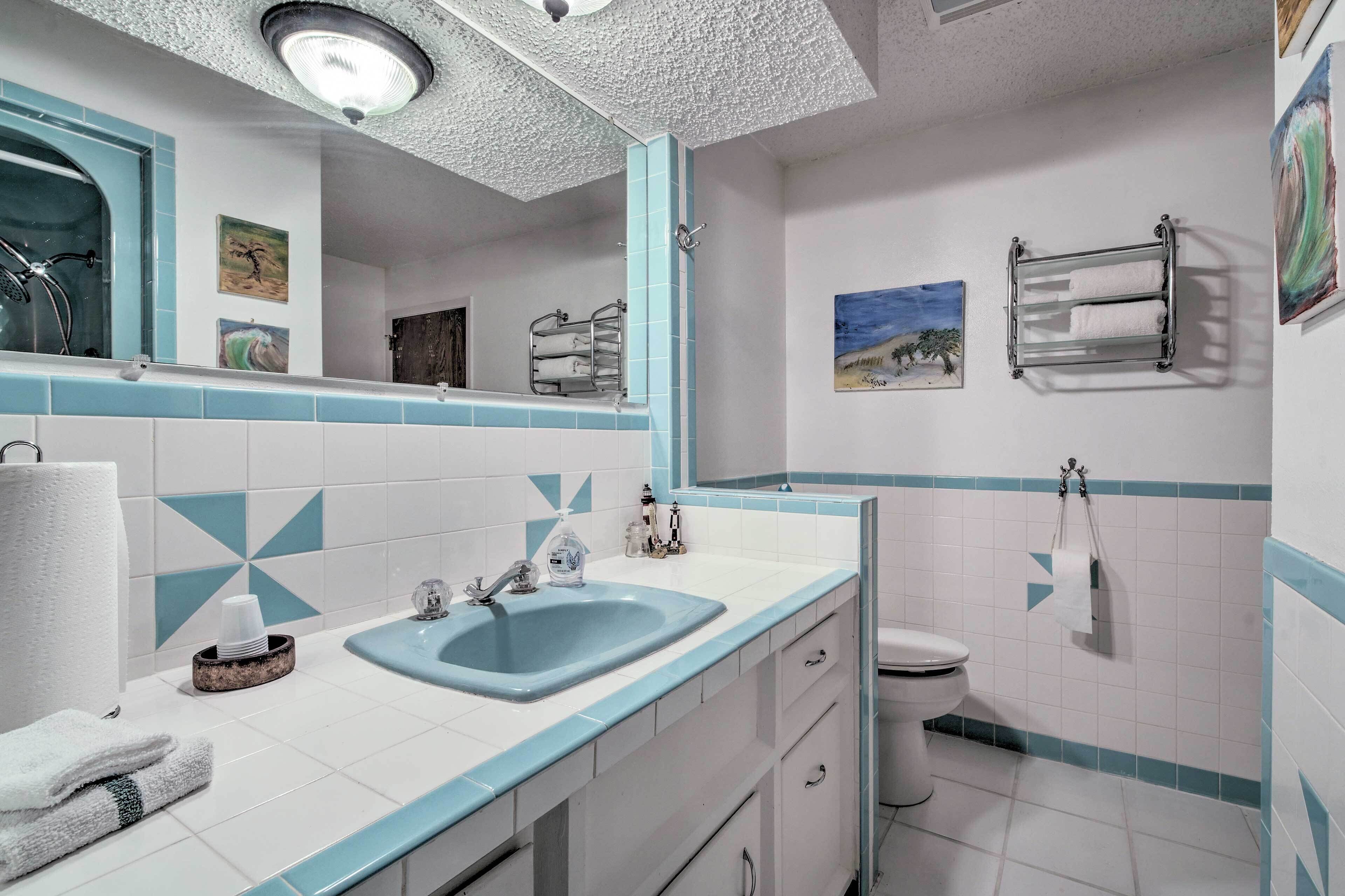 A bathroom with a sink, mirror, toilet, and towel rack.