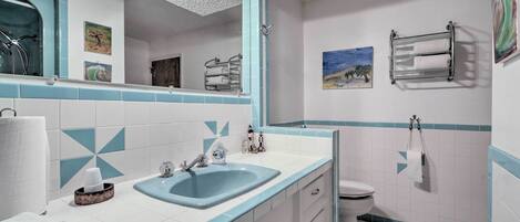 A bathroom with a sink, mirror, toilet, and towel rack.