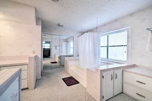 A bathroom with a bathtub, a shower, a sink, and a mirror.