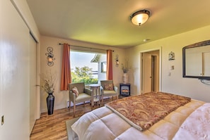 A bedroom with a large bed, two armchairs, a small table, a vase with branches, and a fireplace. - Waterfront Home ~ 6 Mi to Olympic National Park! (Port Angeles)