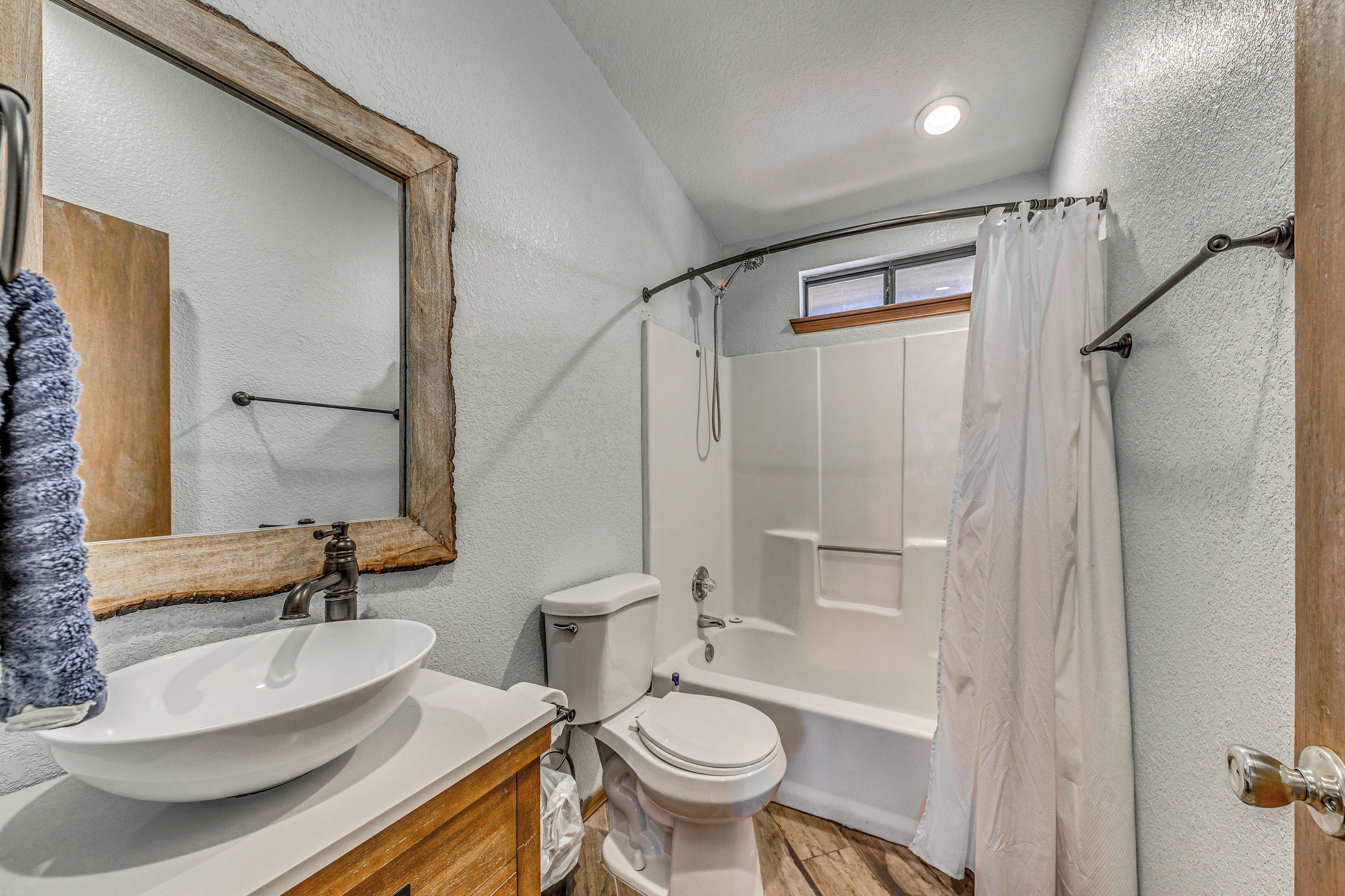 Une salle de bain avec un meuble-lavabo en bois, un lavabo blanc, des toilettes et une baignoire.