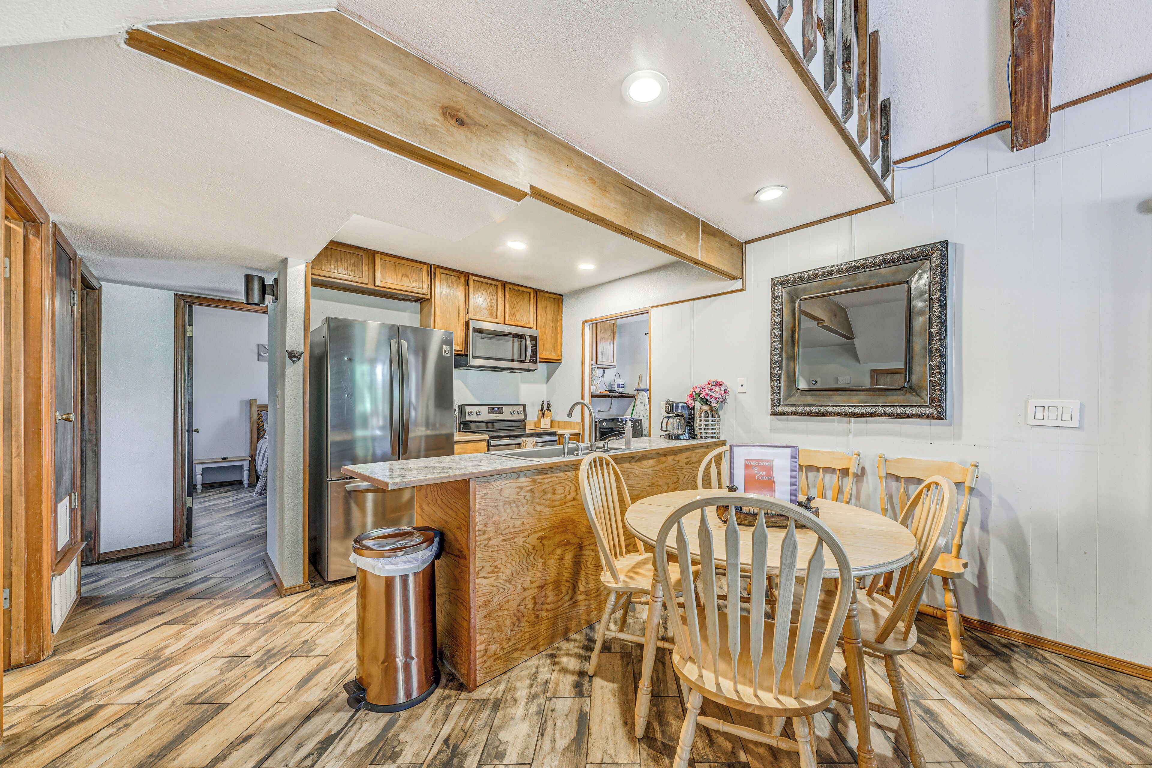 A modern kitchen with wooden cabinets, a stainless steel refrigerator, a microwave, and a wooden dining table with chairs.