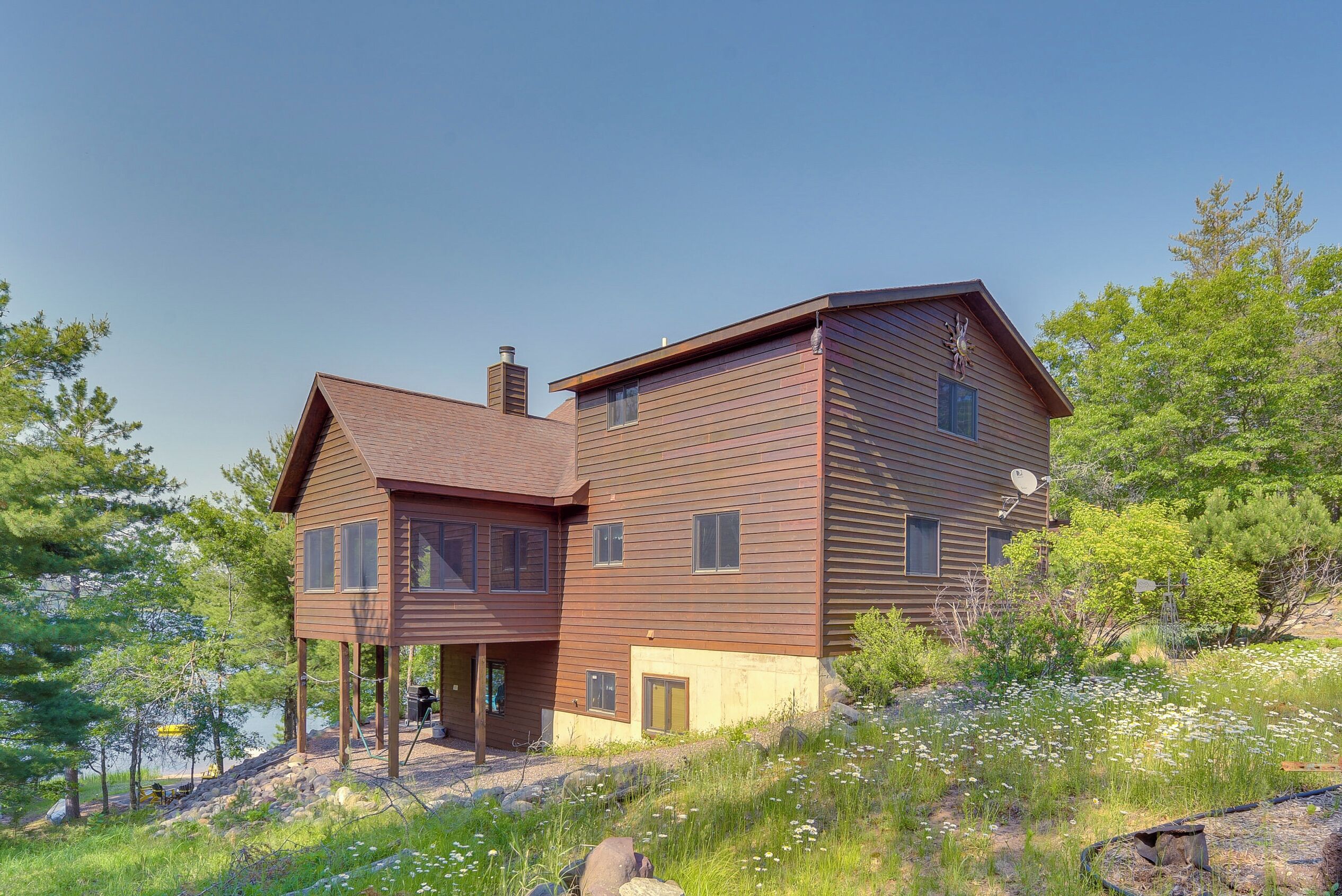 A modern two-story house with a wooden exterior, a covered porch, and a view of a natural landscape.