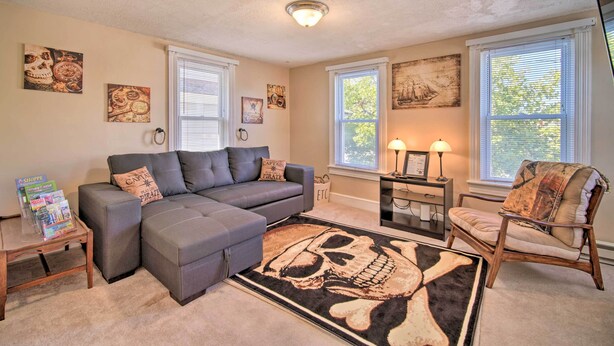A living room with a gray sectional sofa, a wooden coffee table, a patterned rug, and artwork on the walls. - Family-friendly Wildwood Apt: Bike to Beach! (Wildwood)