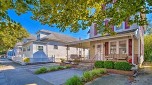 A two-story house with a front porch, a small garden, and a visible staircase leading to the entrance. - Family-friendly Wildwood Apt: Bike to Beach! (Wildwood)