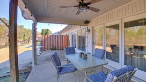 A covered patio with a table and chairs, a ceiling fan, and large windows. - Lake Balboa Access: Home w/ Dock & Yard (Hot Springs Village)