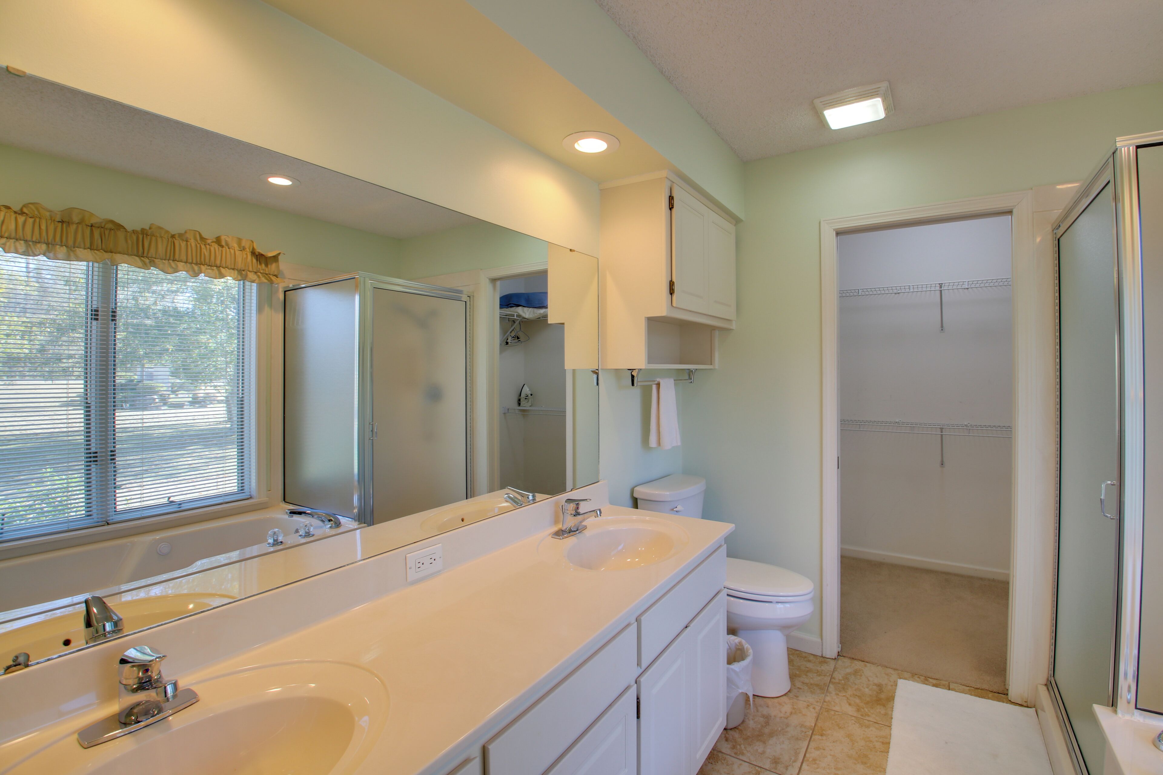 A bathroom with a large mirror, a sink, a toilet, and a shower.