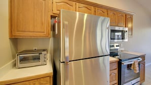 A kitchen with wooden cabinets, a stainless steel refrigerator, a microwave, a toaster, and an oven. - Lake Balboa Access: Home w/ Dock & Yard (Hot Springs Village)
