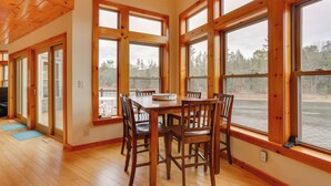 A dining area with a wooden table and chairs, large windows with a view of a body of water, and a wooden ceiling. - Pet-friendly Hancock Home on the Delaware River! (Hancock)